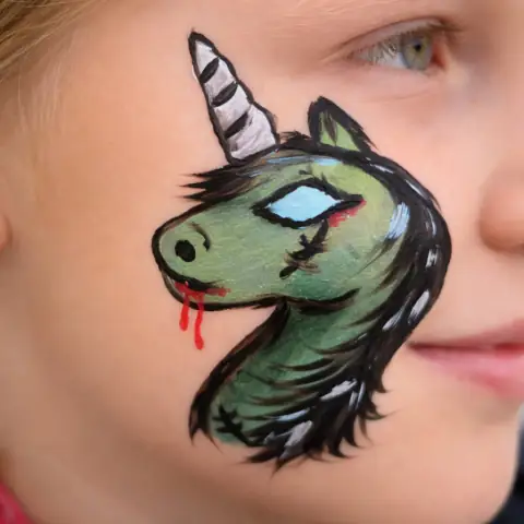 Green unicorn painted on a cheek